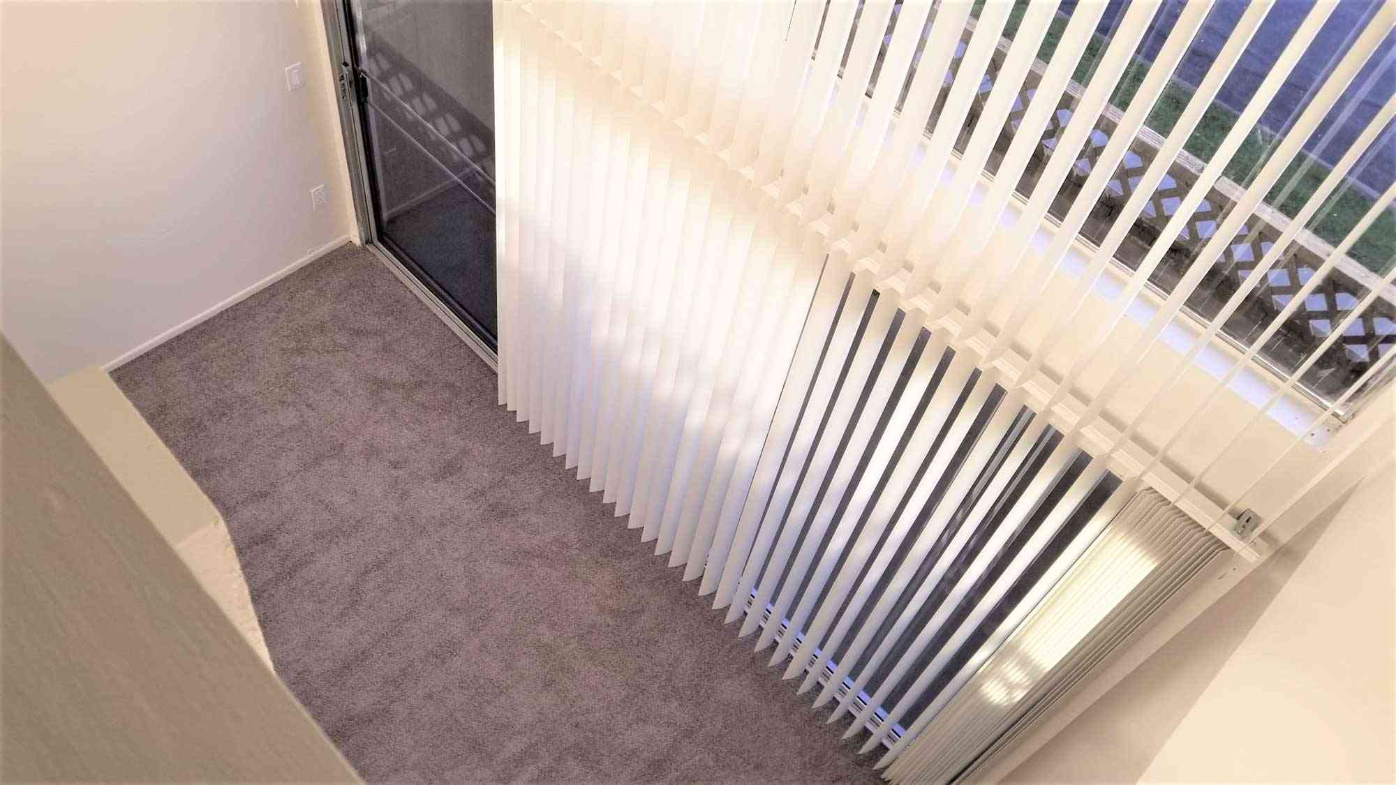 living room vertical blinds and private balcony access